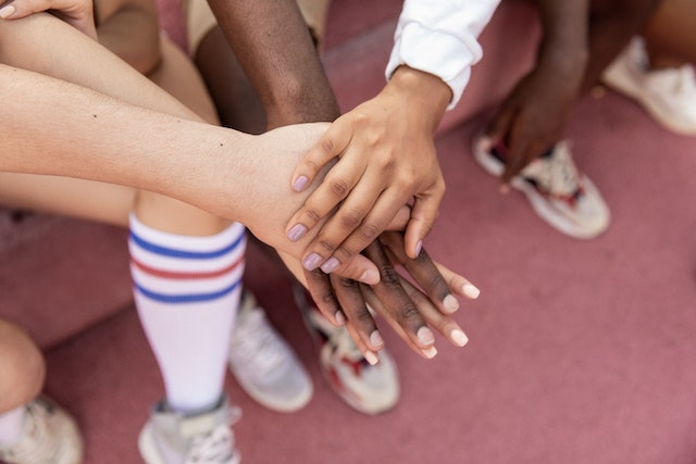 Multiracial athletic team putting hands together before a cheer.