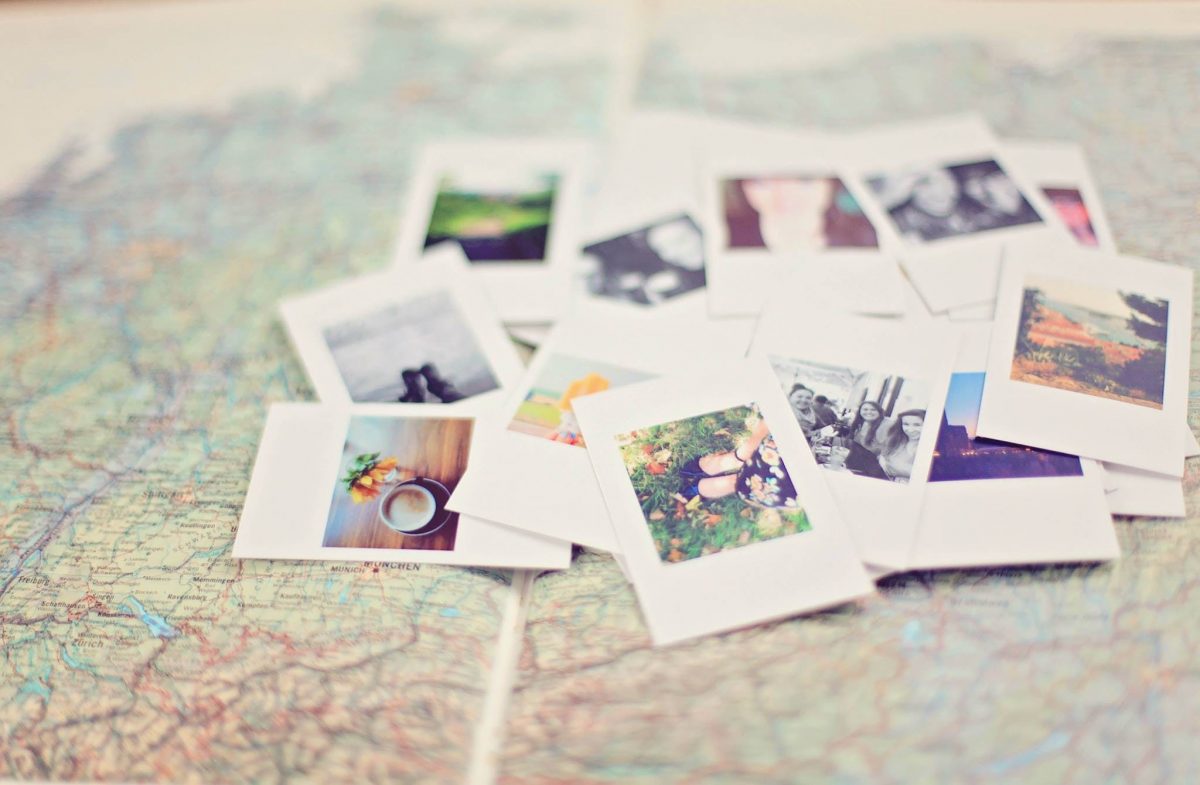A pile of photographs lie scattered on top of a map. 
