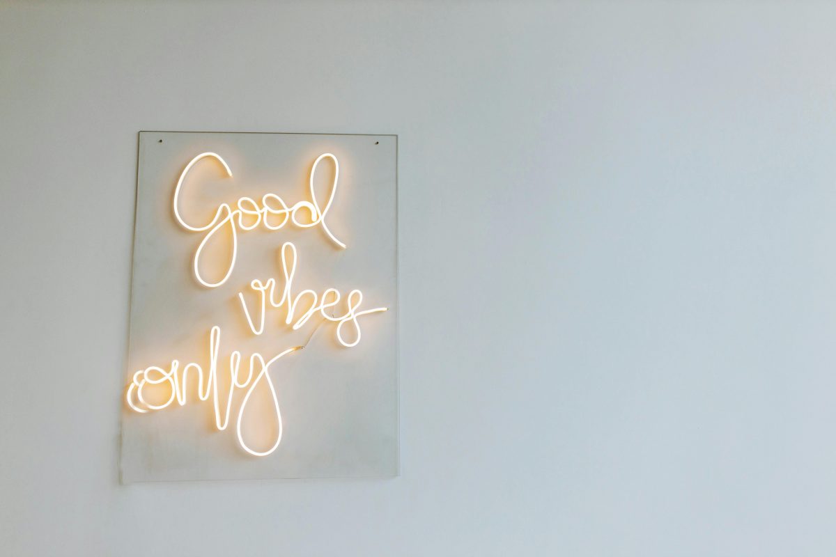 A white wall with a glowing neon sign in white light that says "good vibes only."