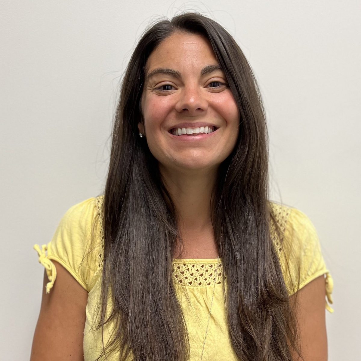 Portrait of Christine Wenzel wearing a yellow, short-sleeved blouse.